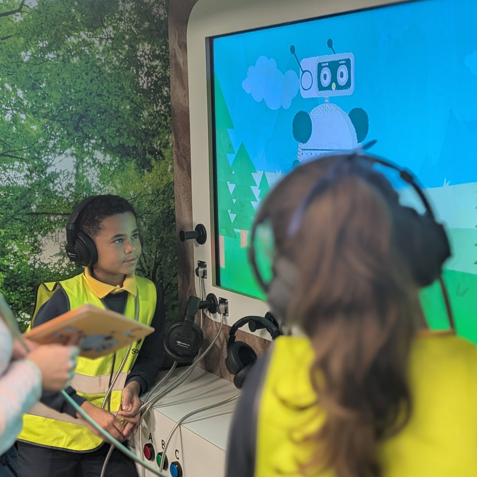 Wastesavers - Two children in yellow vests and a teacher interact with a digital educational game on a large screen.